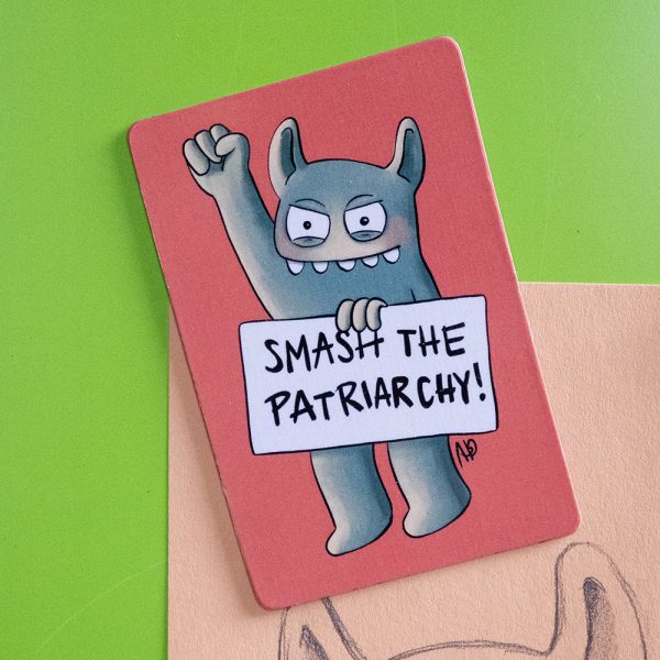 Ein grünes Monster hält ein Schild in der Hand auf dem "Smash the Patriarchy!" steht und reckt den Arm in die Höhe
